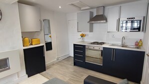 A modern kitchen with a built-in oven, a stove, and a microwave. There is a sink with a faucet, and a clock on the wall.