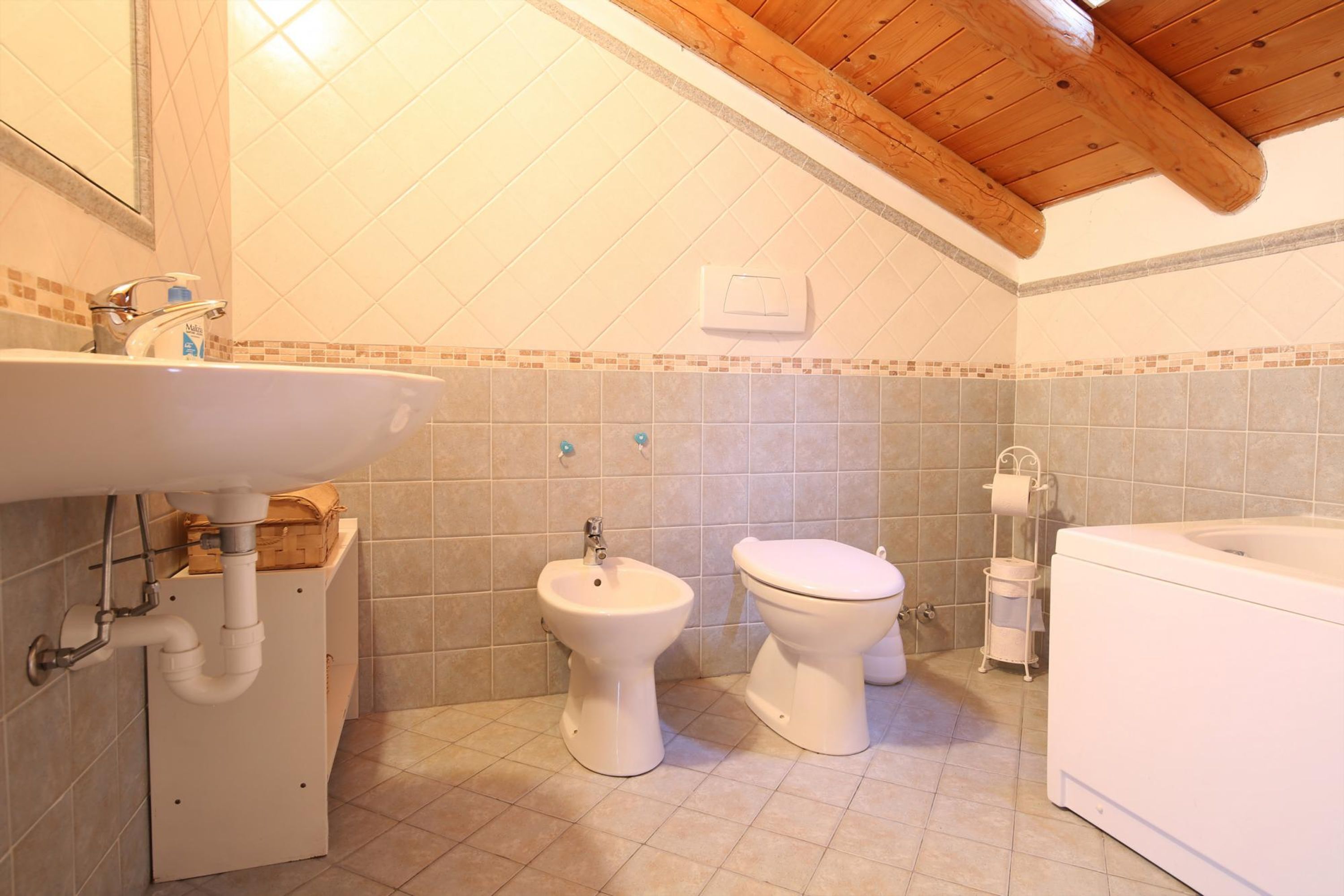 A bathroom with a sink, bidet, toilet, and bathtub.