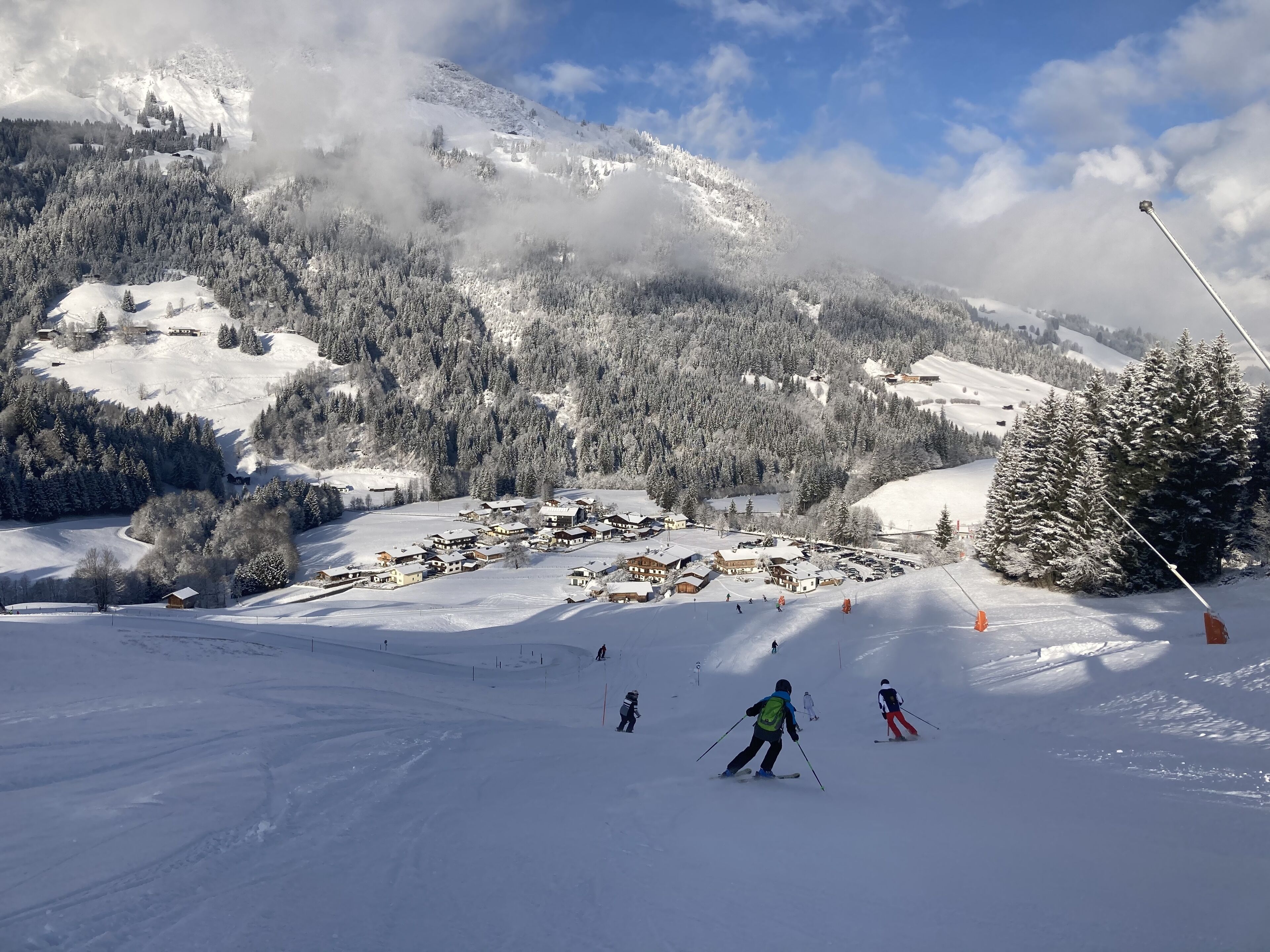 Een besneeuwd berglandschap met een skigebied, inclusief skipistes, een klein dorp en beboste gebieden.