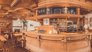 Un restaurante acogedor con interiores de madera, varias mesas para comer y una zona de bar.