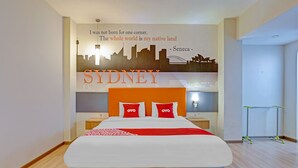 Habitación de hotel con cama, un mural del horizonte urbano y una cita de Séneca.
