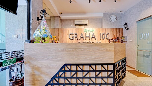 Un mostrador de recepción con detalles de madera y un letrero que dice "Syariah Graha 100 guesthouse".
