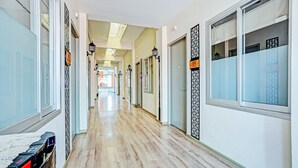 Un pasillo de hotel con suelo de madera, puertas de cristal y faroles decorativos.