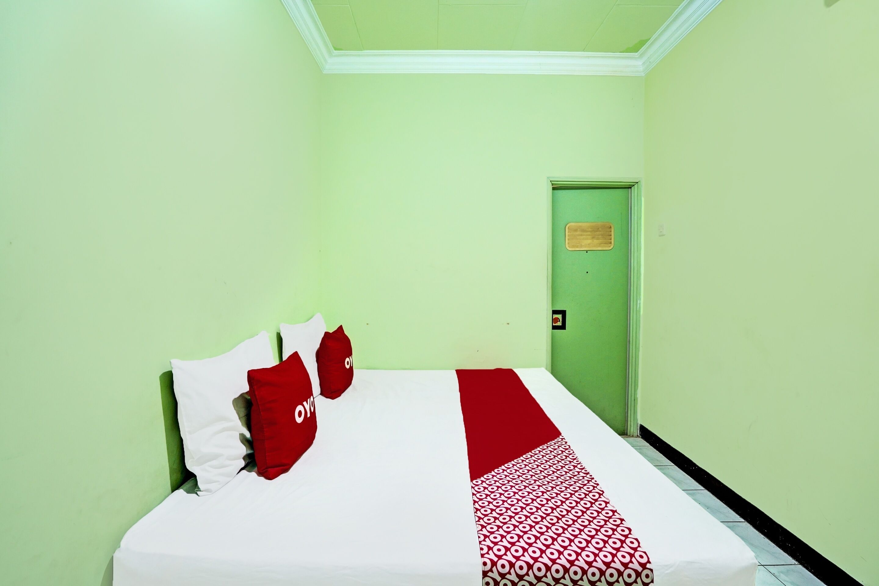 A hotel room with a bed, green walls, and a door with a sign.