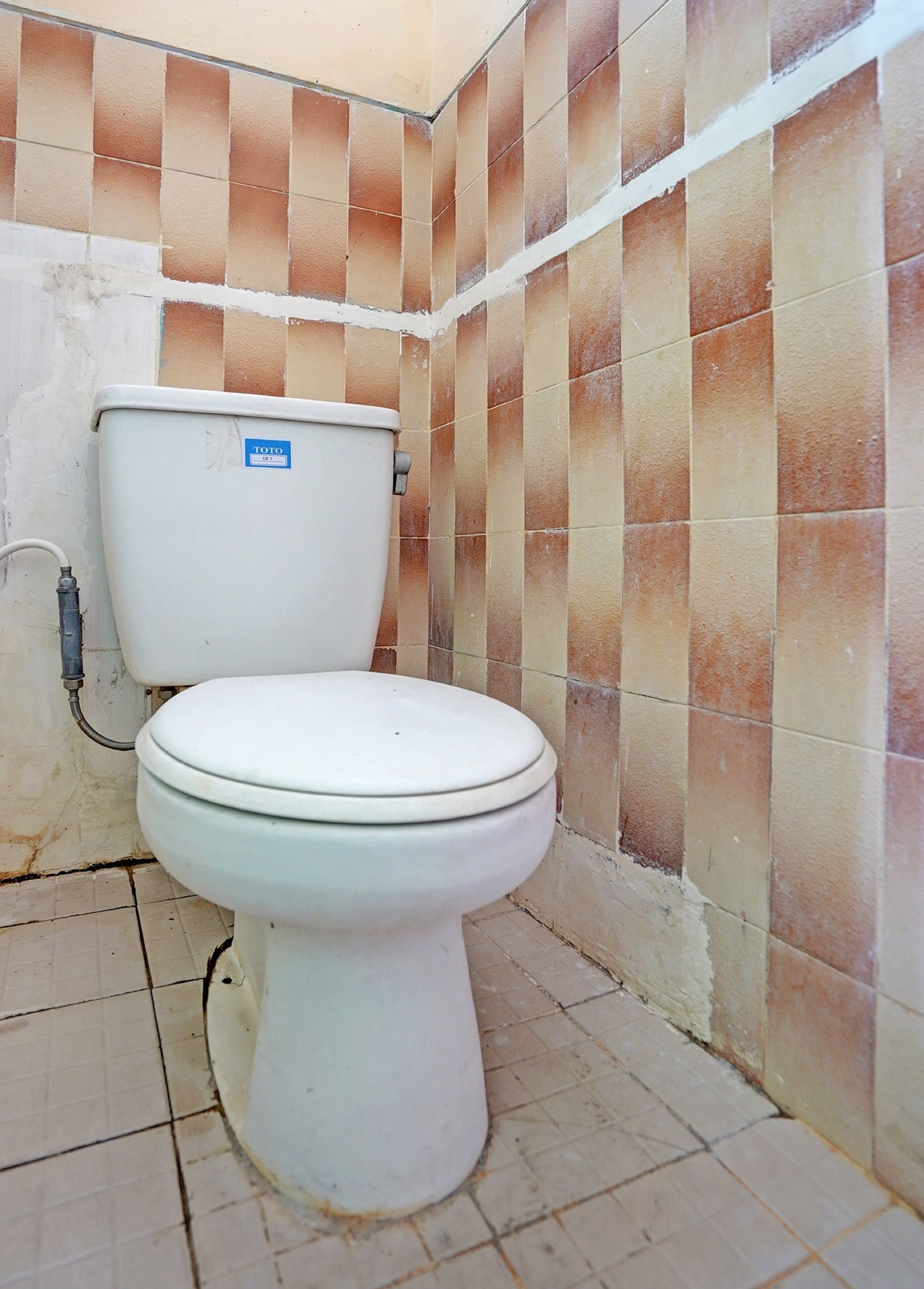 Et toilet i et badeværelse med flisegulv og fliserede vægge.