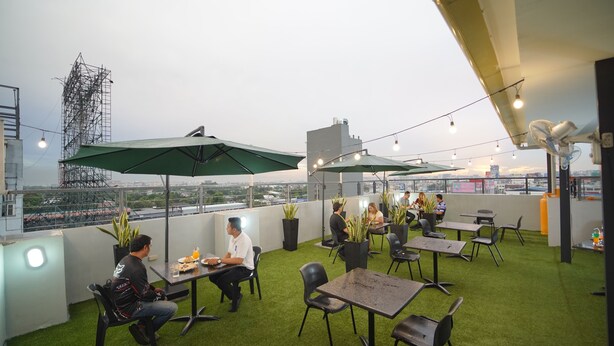 A rooftop terrace with green artificial grass, outdoor seating, and umbrellas. - ARZO Hotel Premier (Makati)