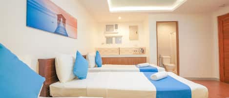 A hotel room with two beds, a bathroom, and a view of the sea.
