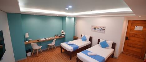 A modern hotel room with two beds, a desk, and a chair.