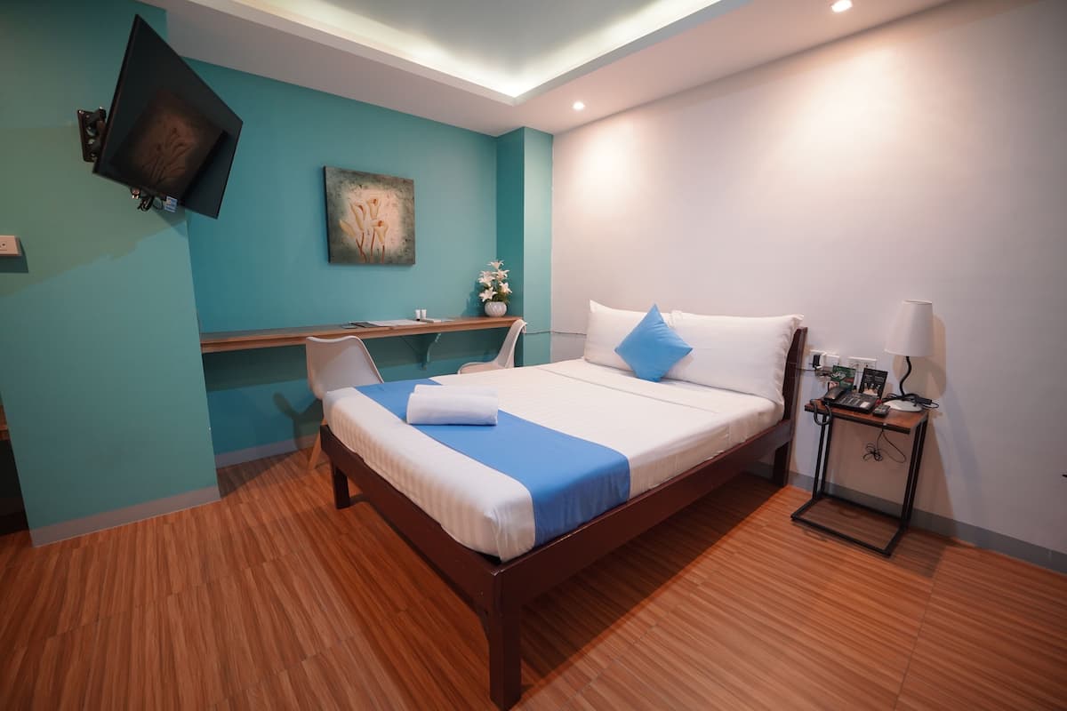 Ein modernes Hotelzimmer mit einem hölzernen Bett, einem Schreibtisch und einem an der Wand montierten Fernseher.