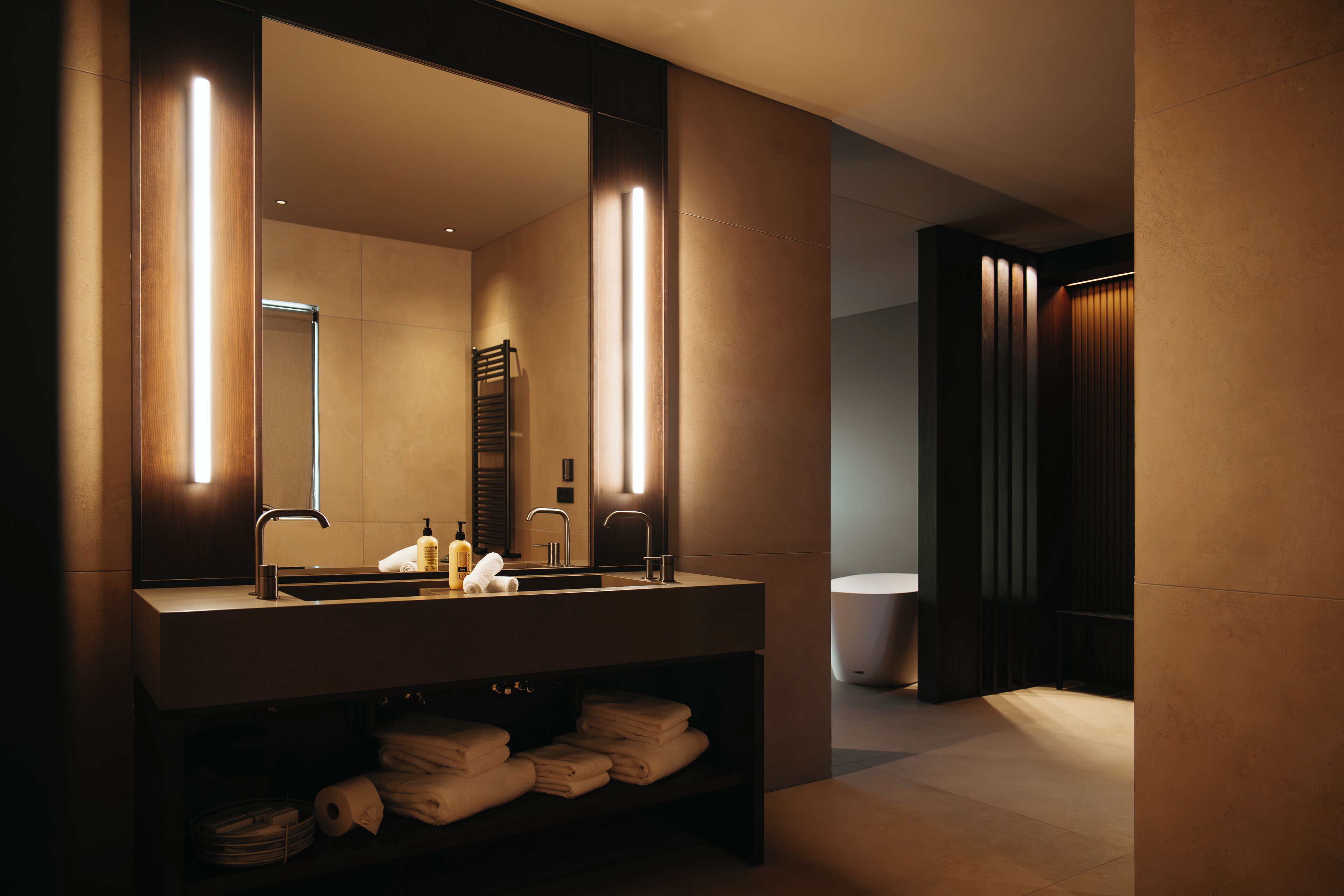 A modern bathroom with a large mirror, two sinks, and a towel rack.