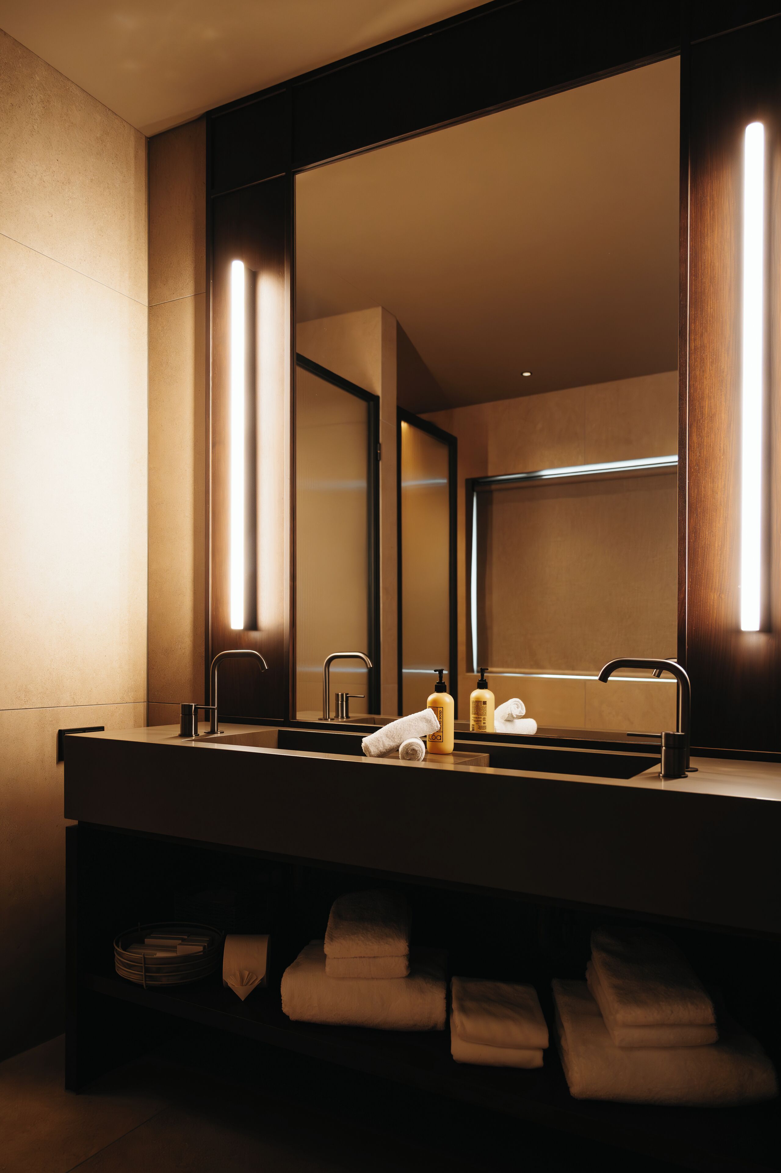 A modern bathroom with a large mirror, two sinks, and a towel rack.