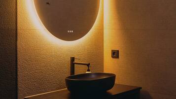Un baño con un espejo redondo, un lavabo, un inodoro y un dispensador de pañuelos.