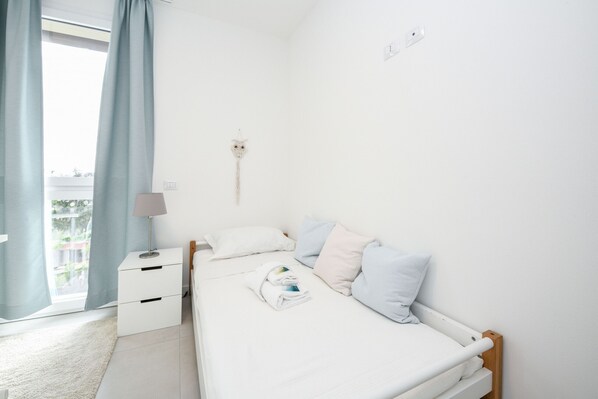 Un dormitorio minimalista con cama, mesita de noche y una lámpara fijada a la pared.