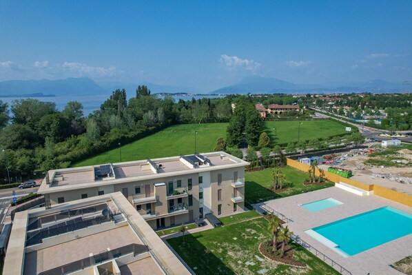 Un edificio moderno con terraza en la azotea, piscina y vistas al mar y a las montañas.