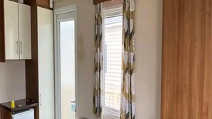 A compact living space with a kitchenette, a built-in bench with seating, a small table, and a fireplace. - Heacham 2 bed Superior Caravan With Pets go Free (King's Lynn)