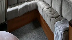 A corner sofa in a room with a view of mobile homes outside. - Heacham 2 bed Superior Caravan With Pets go Free (King's Lynn)