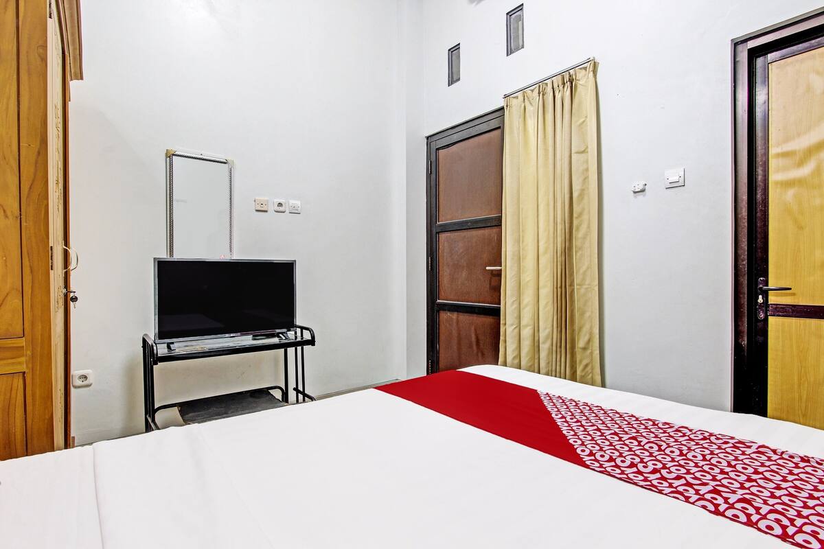 A hotel room with a bed, a TV, a wardrobe, and a door.