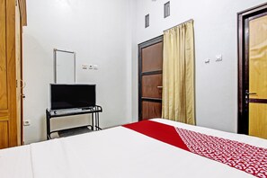 Una habitación de hotel con cama, televisión, armario y puerta.
