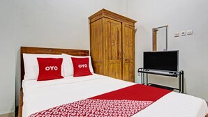 Et hotelværelse med seng, garderobeskab og fjernsyn på et stativ.