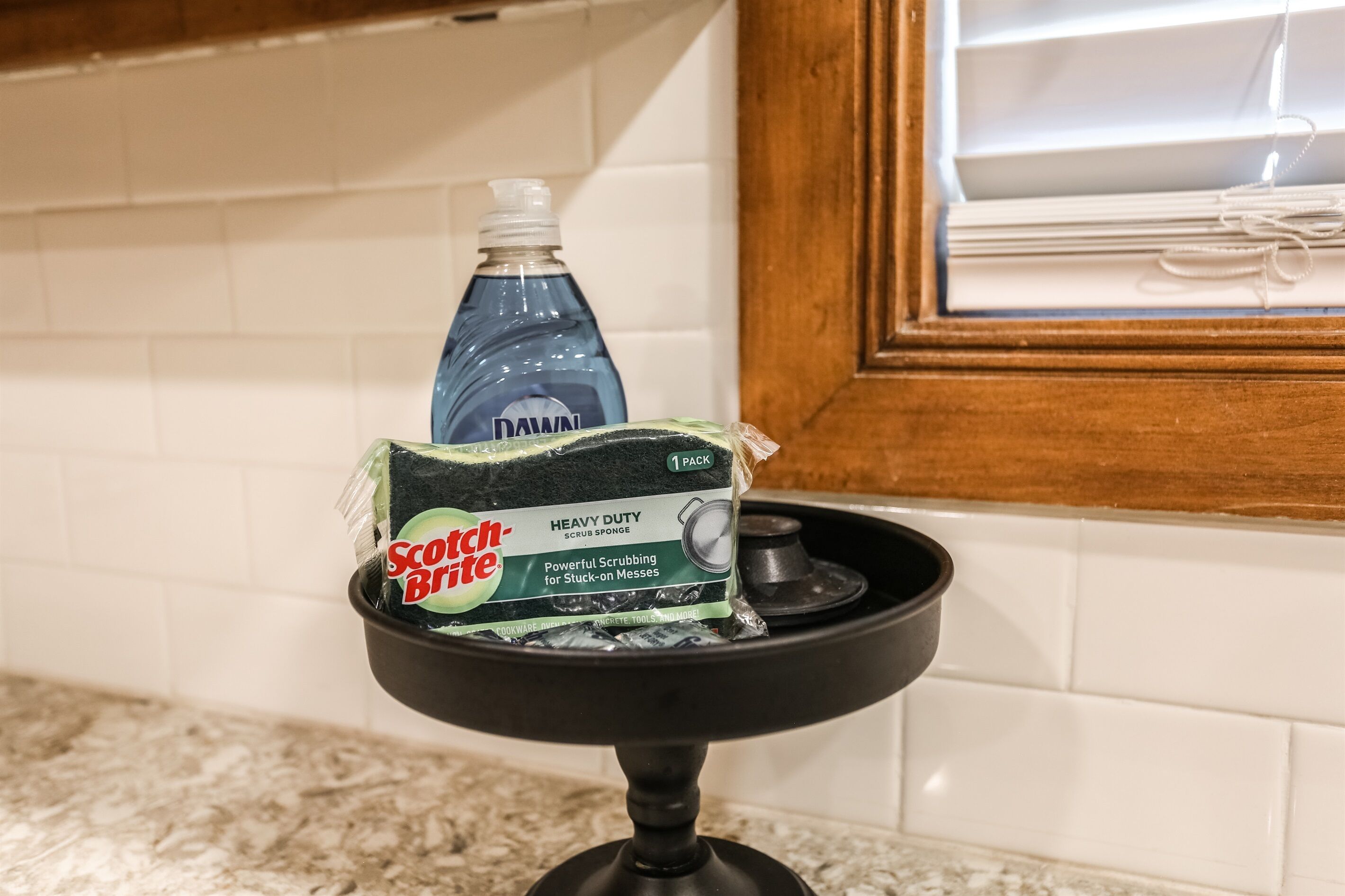 Un lavamanos de cocina con una botella de detergente Dawn y una esponja Scotch-Brite.