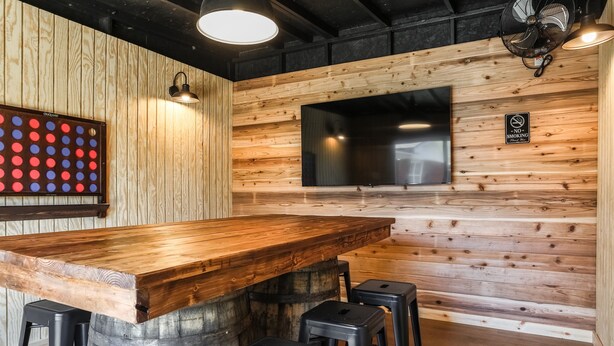 Un espace bar avec un comptoir en bois, des tabourets, un grand écran de télévision et un panneau indiquant qu'il est interdit de fumer.