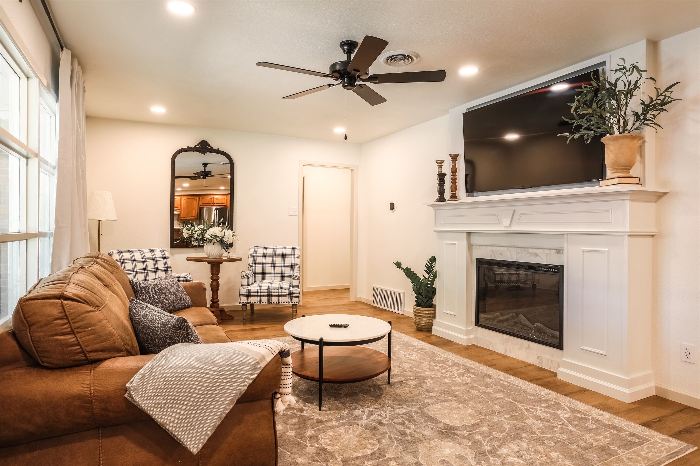 A living room with a brown leather sofa, a round coffee table, a fireplace, and a large flat-screen TV.