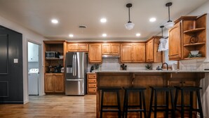 Une cuisine moderne avec des meubles en bois, des appareils en acier inoxydable et un îlot central doté de tabourets de bar.