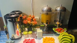 A buffet table with various food items, including watermelon, cheese, and bananas, along with condiments and utensils. - Luang Prabang Hostel (Luang Prabang)