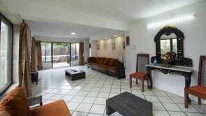 Ein geräumiges Wohnzimmer mit Sofa, Sesseln, Couchtisch und dekorativem Spiegel.