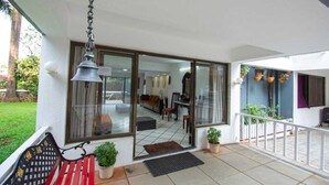 Ein modernes Haus mit Glastür zu einem Wohnbereich, einem Balkon mit Sitzbank und Kübelpflanzen.