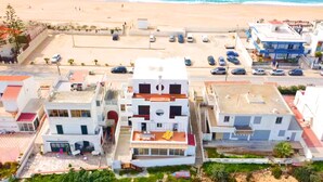 Un hotel sulla costa con diversi edifici, un'area di parcheggio e una spiaggia sullo sfondo.