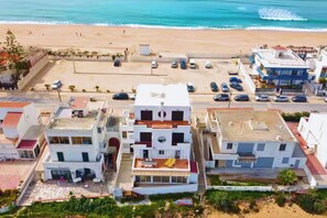 A coastal building complex with multiple structures, a parking area, and a beach in the background. - Casa na Ria: 7 Camas, na Praia da Ilha de Faro (Faro)