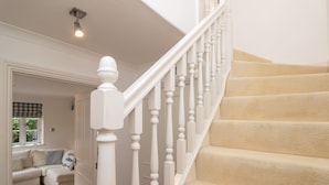 A staircase with white balusters and beige carpeted steps. - November Cottage (Dartmouth)
