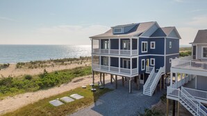 Uma casa à beira-mar com várias varandas e vista para a praia e o oceano.