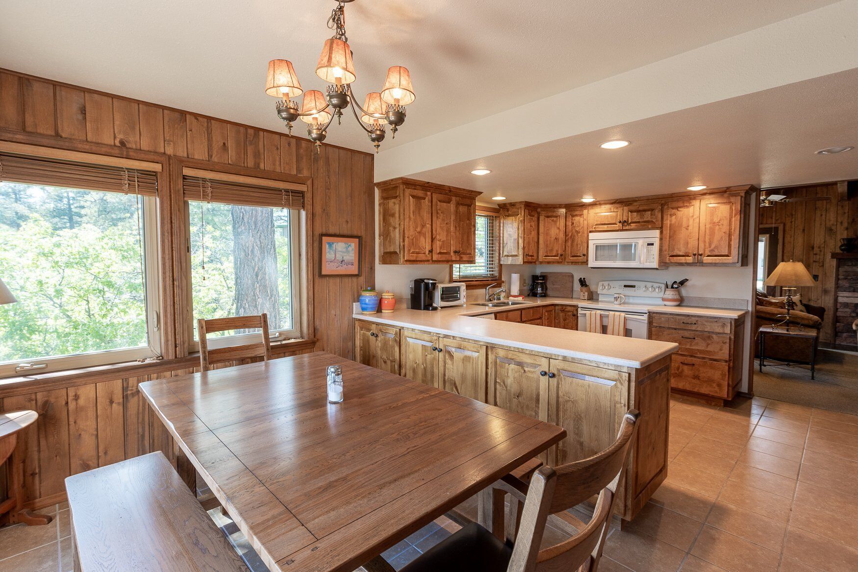 A kitchen with wooden cabinets, a central island, a dining table, and a chandelier.