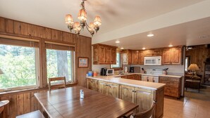 A kitchen with wooden cabinets, a central island, a dining table, and a chandelier. - Near Lake Hatcher and walk to San Juan Forest, Quiet Area. (Pagosa Springs)