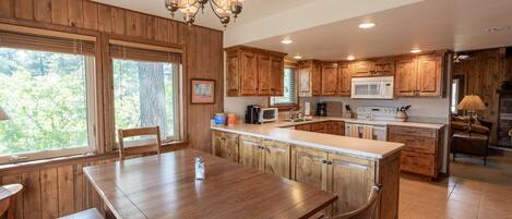 A kitchen with wooden cabinets, a central island, a dining table, and a chandelier.