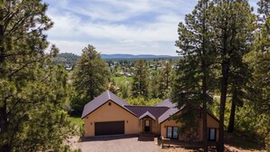 A single-story house with a garage, surrounded by tall pine trees, set in a rural area with a clear view of distant hills. - Near Lake Hatcher and walk to San Juan Forest, Quiet Area. (Pagosa Springs)