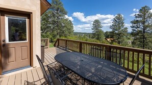 A deck with a table and chairs, a door, and a view of trees and a distant landscape. - Near Lake Hatcher and walk to San Juan Forest, Quiet Area. (Pagosa Springs)