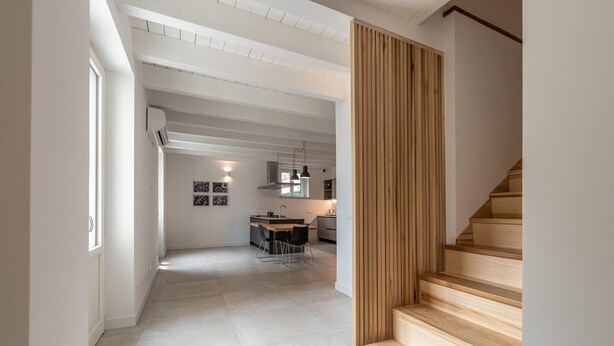 A spacious hallway with a staircase leading to a second floor. The hallway features a modern kitchen area with a dining table and chairs, and a visible air conditioning unit. - Appartamento Principe di Camporeale con Terrazza (Palermo)