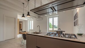 A modern kitchen with a central island, stainless steel appliances, and a view of the outdoors. - Appartamento Principe di Camporeale con Terrazza (Palermo)