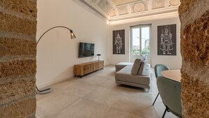 A modern living room with a TV, a sofa, a dining table, and artwork on the walls. - Appartamento Principe di Camporeale con Terrazza (Palermo)