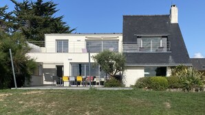 Een modern huis met twee verdiepingen, een plat dak, grote ramen en een balkon.