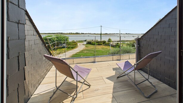Een balkon met twee stoelen en uitzicht op een rivier en het verre landschap.