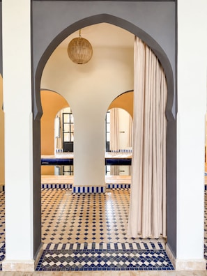 Un pasillo con suelo de baldosas, un arco de entrada y una lámpara colgante.