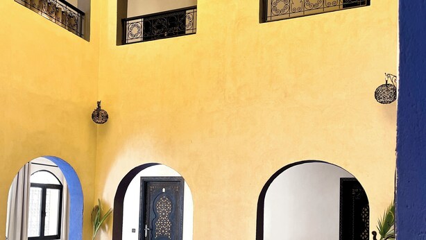 A pool area with a tiled floor, arched doorways, and potted plants. - Riad La Luna (Merzouga)