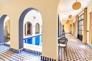 A hotel corridor with a pool, arches, and patterned flooring.