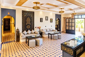 A modern living room with a sofa, ottomans, a coffee table, and a decorative wall piece.