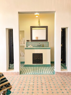 A bathroom with a checkered floor, a tiled sink area, and a mirror with a decorative frame.