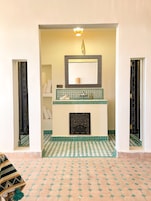 Un baño con piso a cuadros, zona de lavamanos con azulejos y un espejo con marco decorativo.